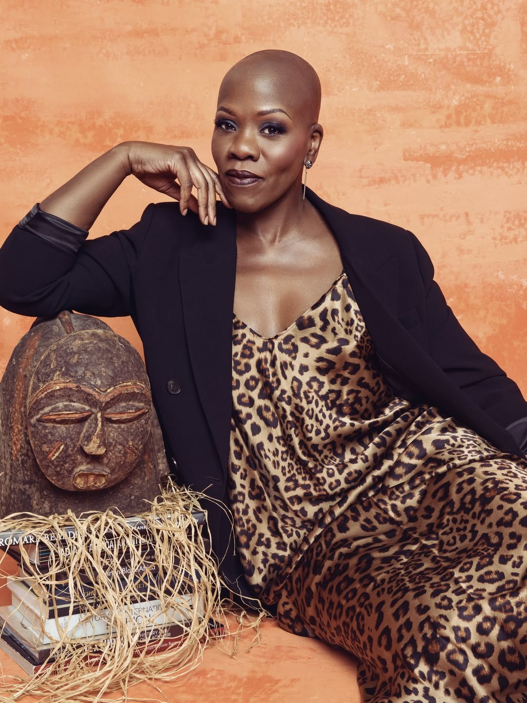 Demeatria Boccella, FashionAFRICANA founder, seated with African mask and fashion books
