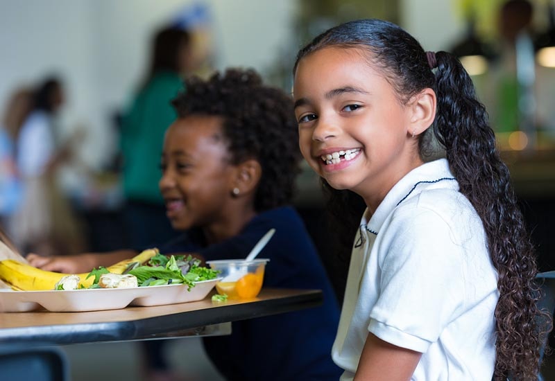Girl eating a healthy school lunch in a cafeteria