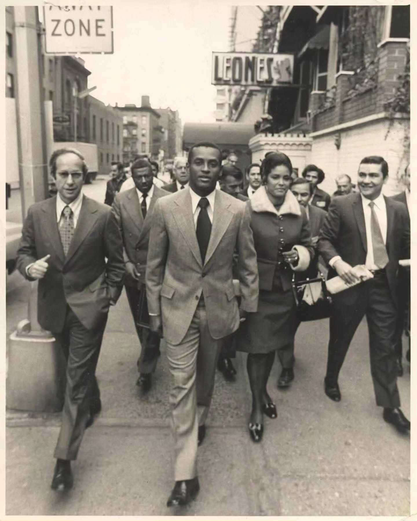 Roberto Clemente walking confidently down a city street in a suit